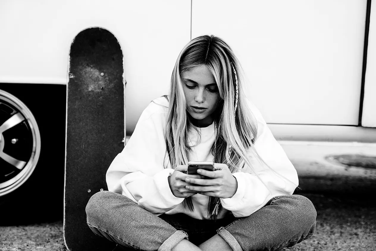 Junge Frau mit Handy und Skateboard
