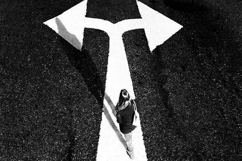 Image of a person standing in front of an arrow pointing in two directions.