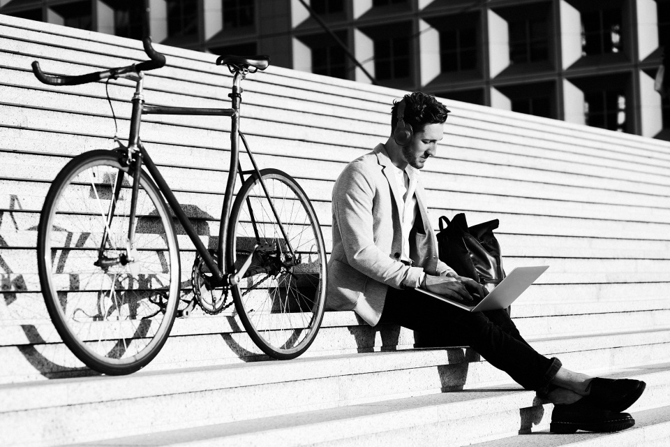 Persona che lavora al computer portatile all’aperto con una bicicletta