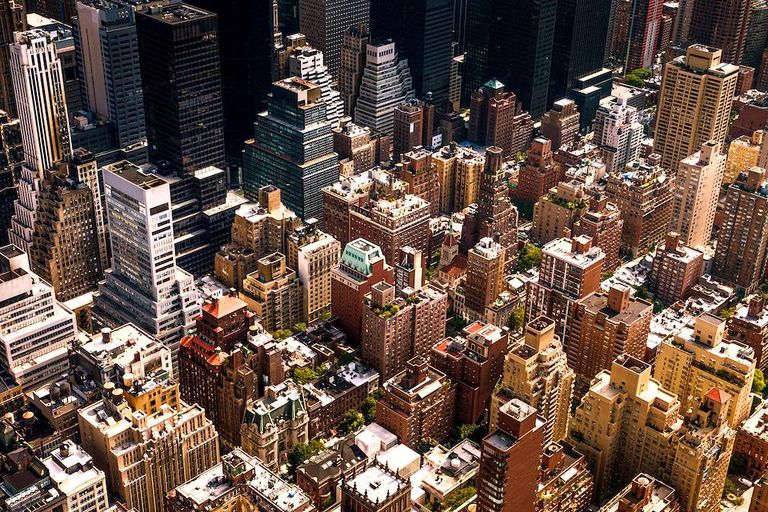 Aerial view of a dense urban cityscape with high-rise buildings and streets between commercial and residential towers.