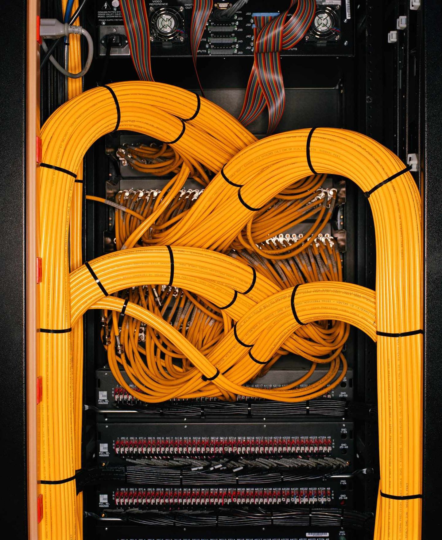 Organized fibre-optic and network cables routed through a data centre communications rack