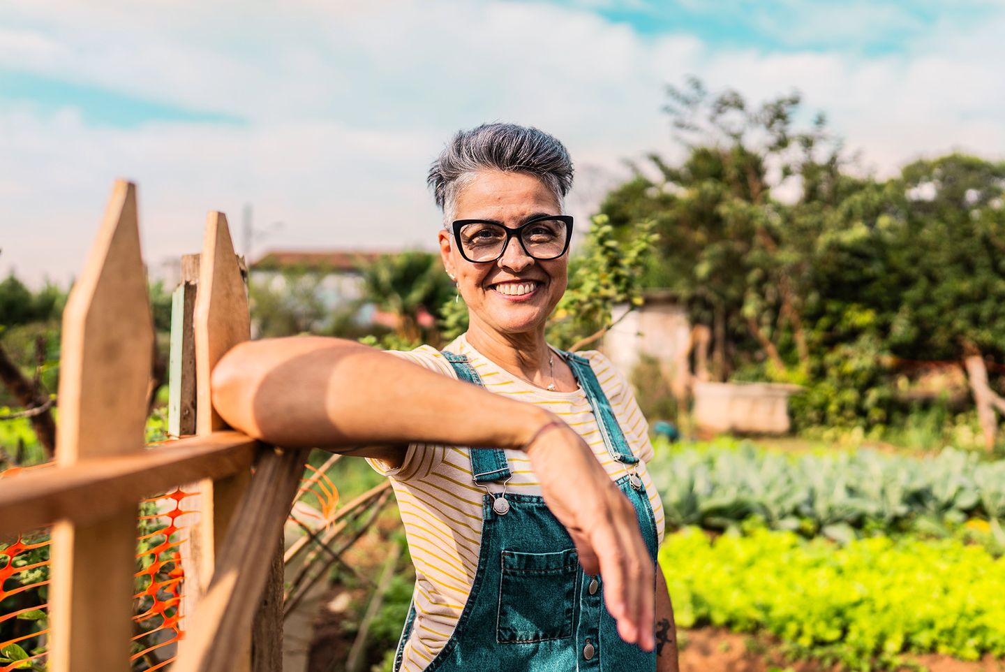 Smiling senior woman leaning on a gate at a garden entrance. BlackRock; iShares; Portrait; individual investor; retirement investor
