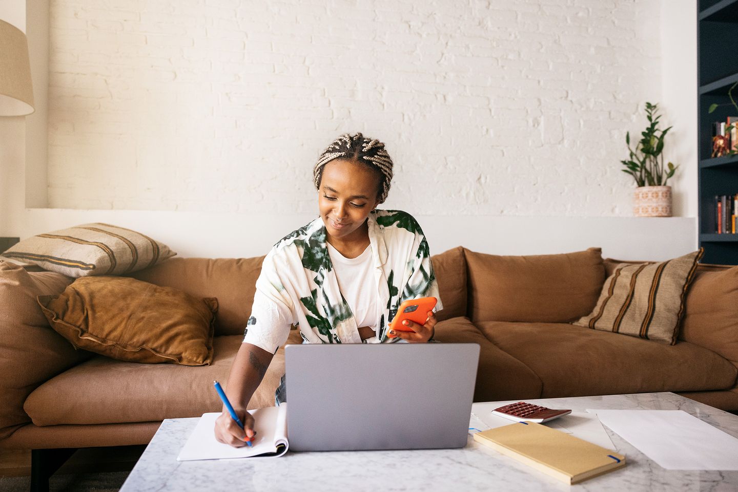 Woman sitting on sofa and using laptop at a marble table. BlackRock; iShares; Portrait; individual investor