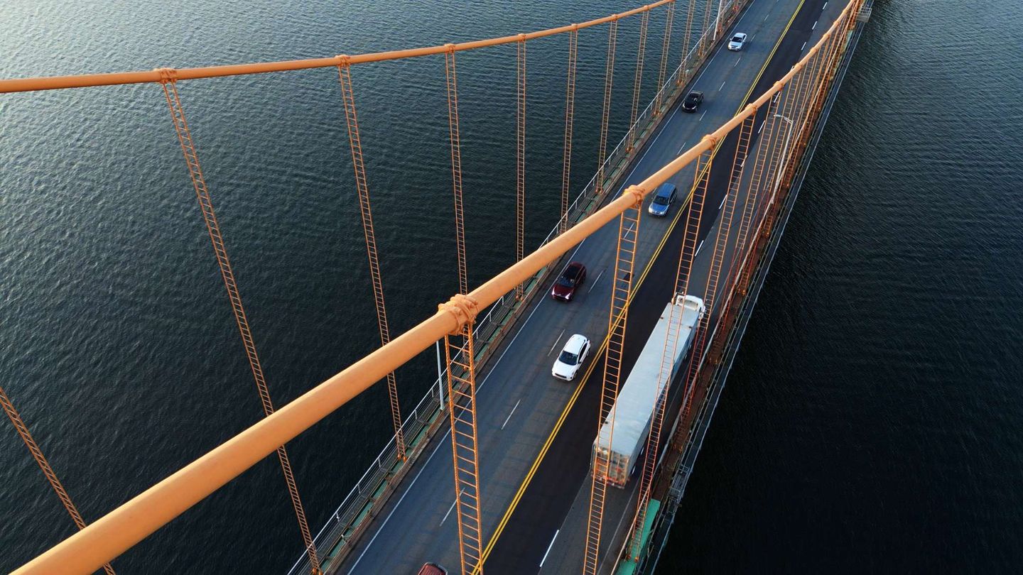 Aerial view of vehicles travelling across a suspension bridge over open water